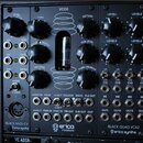 Černý modulární syntetizátor s nápisy VCO2 a BLACK QUAD VCA2. Na panelu jsou umístěny černé oválné knofíky, elektronické vacuum v prostoru uprostřed…
