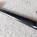 Zadní strana krku a hlavy černé elektrické kytary. Na zadní straně hlavy je text „Made in Korea by Samick Musical Instruments Co., Ltd. Korea“ a pod…