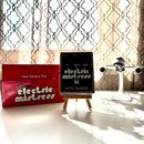 Černý efekt pedál s nápisy RATE, FLANGER DEPTH a CHORUS DEPTH u ovládacích knoflíků. Uprostřed je bílý nápis electric mistress a v dolní části značka…