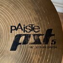 Detailní záběr na mosazný činel s koncentrickým žebrováním povrchu. Na čineli je černý nápis pAiste a pod ním modelové označení PST 5. Dole je uveden…