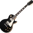 Černá elektrická kytara s tvarem Les Paul, bílým pickguardem a krčkem z tmavého dřeva s trapezoidními vložkami. Na hlavě je bílé logo Gibson a nápisy…