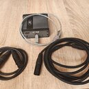 Šedý kovový box s nápisem USB-P a logem Tascam. K boxu je připojen šedý kabel s USB konektorem. Vedle boxu leží dva černé kabely s vícepinovými konek…