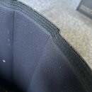 Detailní pohled na horní hranu a vnitřek černého textilního obalu nebo pouzdra. Povrch materiálu je hladký, v horní části je viditelný šev a hrana s…