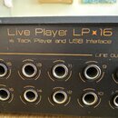 Černý elektronický přístroj s nápisy v žluté barvě. Na horní části je text Live Player LP 16 a pod ním Live Track Player and USB Interface. V dolní č…