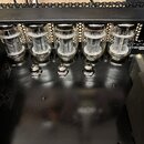 Fotografie zachycuje vnitřek elektronického zařízení, pravděpodobně zesilovače, s pěti zapojenými elektronkami v řadě. Pod každou elektronkou je na č…