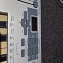 Detailní pohled na ovládací panel stříbrného klávesového nástroje. Jsou vidět tlačítka s nápisy Home, Store, Edit a Enter, digitální displej a posuvn…