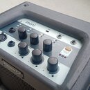 Kompaktní černý kombozesilovač s ovládacím panelem v šedé barvě. Na horní části je nápis mini a USB, dále jsou zde popisky INPUT, VOLUME, PHONES, AUX…