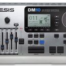 Stříbrný elektronický bicí modul značky Alesis, model DM10 s nápisem HIGH DEFINITION DRUM MODULE WITH DYNAMIC ARTICULATION. Zařízení má digitální dis…