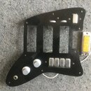 Černý plastový pickguard s vyřezanými otvory pro snímače a ovládací prvky. Je na něm osazeno pět kovových potenciometrů s bílými knoflíky a jeden pře…