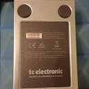 Fotografie zachycuje spodní stranu efekt pedálu v kovovém stříbrném šasi se čtyřmi gumovými nohami. Na černém štítku je uveden nápis tc electronic a…