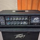 Černý kytarový zesilovač a připojená reprobox s logem Peavey. Na předním panelu zesilovače je nápis CENTURION MARK III SERIES MADE IN USA EST 1979. P…