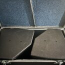 Dva černé podiové monitory s texturovaným povrchem umístěné v transportním kufru. Kufr má vnitřní stěny vyloženy modrou plstí a kovové uzavírací zámk…