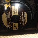 Fotografie zachycuje zadní část reproduktoru s kulatým štítkem. Na štítku je vidět logo Fender a nápisy SPECIALLY DESIGNED, MUSICAL INSTRUMENT CORPOR…