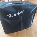 Černý textilní kryt na hudební zařízení s rukojetí na horní straně. Na přední části je bílý nápis Fender®. Povrch materiálu vykazuje mírné pomačkání.
