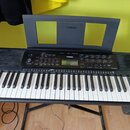 Černý digitální klavír s bílými a černými klávesami, umístěný na černém stojanu. Na horním panelu a na notovém pultu je bílé logo YAMAHA. V pravé čás…