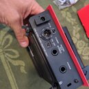 Detailní pohled na zadní panel černého elektronického zařízení. Jsou zde viditelné konektory a nápisy: „DC IN“, „USE BOSS PSA(S) ADAPTOR ONLY“, přepí…