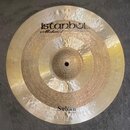 Kruhová mosazná činely s viditelným kování povrchu. Na horní části je nápis istanbul Mehmet a text Handmade Cymbals from Turkey, ve spodní části nápi…