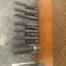 Detailní pohled na hnědé plastové klávesy elektronického nástroje v dřevěném korpusu. Na dřevěné části jsou zlatým písmem nápisy MEMORY CHORDS, SEVEN…