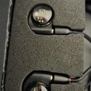 Dva černá vnitroušní sluchátka umístěná v černé pěnové vložce. Sluchátka mají průhledné kryty, skrze které je vidět vnitřní elektronika. Na povrchu n…