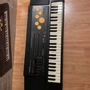 Černý elektronický klávesový nástroj s bílými a černými klávesami. Na ovládacím panelu jsou nápisy CASIO MT-640, DYNAMIC BASS a PERCUSSION PADS. V ho…