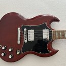 Tmavě červená elektrická kytara s černým pickguardem a dvěma humbuckery. Na hmatníku jsou vidět trapezoidní vložky. Nástroj má čtyři ovládací knofíky…