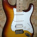 Elektrická kytara s trupem v barevnosti sunburst a bílým pickguardem. Nástroj má tři snímače (dva jednoduché a jeden double-coil u kobylky), tři bílé…