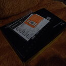 Černá krabice s nápisy CREATIVE SAMPLER a P-6. Na horní straně je logo Roland a označení P-6 s textem Read Me First. Na krabici leží bílý papírový ná…