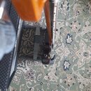 Fotografie zachycuje detail oranžové elektrické kytary umístěné v černém stojanu. Nástroj má lesklý povrch a viditelnou hmatník s pražci. Žádné značk…