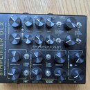 Černý kytarový procesor s nápisem SIMPLIFIER DLX a logem DSM HUMBOLDT ELECTRONICS. Zařízení obsahuje několik otočných potenciometrů s popisky jako LE…