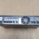 Zadní strana černého rackového zesilovače. Na šasi jsou vidět nápisy Crown, XTi a označení modelu XTi 4002. Zařízení obsahuje různé konektory, včetně…