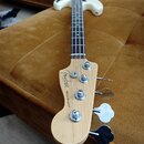 Elektrická basová kytara s bílým trupem a světle hnědým krčkem. Na hlavě nástroje je černé logo „Fender“ a pod ním nápis „PRECISION BASS®“. Nástroj j…