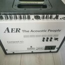 Černý akustický zesilovač s bílým předním panelem. Na panelu je nápis AER The Acoustic People a modelové označení Compact 603 twin channel acoustic a…