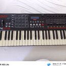 Černý MIDI kontrolér s klávesnicí. Na levé straně je červené logo AKAI PROFESSIONAL a bílý nápis MPK249. Horní panel obsahuje displej s logem AKAI PR…