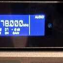Černý rackový接收器 s modrým displejem, na kterém je zobrazen text STEREO, 478.000 MHzs, AUDIO a další hodnoty (L R, GAIN). Na předním panelu jsou nápis…