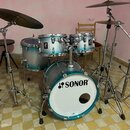 Modrostříbrná bicí souprava značky SONOR. Sestává z basového bubnu s bílým předním koženem a nápisem SONOR, dvou tomů a jednoho floor tomu. Souprava…