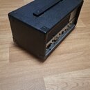 Černý kytarový kombozesilovač s povrchem z texturovaného vinylu a plastovými rohy. Na zadní straně jsou vidět konektory, přepínače a ventilační mřížk…