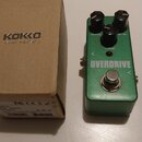 Zelený efekt pedál s nápisem OVERDRIVE a tři černé ovládací knoflíky s popisky DRIVE, LEVEL a TONE. Nad nápisem se nachází malá červená kontrolka. Ve…