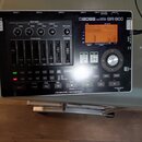Černý digitální nahrávač s nápisem BOSS DIGITAL RECORDER BR-800. Zařízení obsahuje displej, několik posuvníků track mixeru a ovládací tlačítka, z nic…