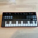 Černý analogový syntetizátor s červeným rámem a bílo-černou klaviaturou. V pravém horním rohu je logo LUNA a nápis SYNTH PRO, v horní části uprostřed…