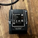 Černý bezdrátový přijímač s připojeným kabelem a konektorem typu jack. Na zadní straně je štítek s nápisy SENNHEISER, EK 100 G4, Diversity Receiver,…