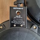 Detailní pohled na zadní stranu černého elektronického padu. Na štítku je uveden nápis Roland, model PDX-8 DUAL TRIGGER PAD a text Patent: roland.com…