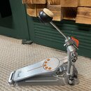Stříbrný kovový basový pedál s oranžovými detaily na šlapce. Na přední části šlapky je čitelné logo Pearl. Povrch vykazuje mírné známky používání a d…