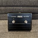 Černý obdélníkový spínací pedál s dvěma stříbrnými tlačítky. Na horní části je bílý nápis CHANNEL PRS PAUL REED SMITH REVERB. Nad každým tlačítkem se…