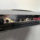 Zadní panel kytarového komba v šedém vinylu s chromovaným kovovým krytem. Na panelu je nápis MAINS INPUT 230V ~ 50Hz, logo Marshall a text Made in En…
