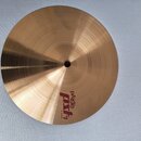 Kruhový mosazný činel s viditelným soustředným broušením povrchu. Na spodní části je červeně a černě vyvedené logo Paiste PSL a nápis 10" SPLASH. Pov…
