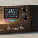 Černý kytarový multi-efekt s integrovaným expresním pedálem. Na zařízení je nápis GE 100 Pro Li AI-Powered Multi-Effects a logo MOOER. Displej zobraz…