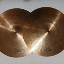 Dva mosazné činely v barvě zlata. Na levém je nápis HI-HAT TOP 13" a logo MAGIC BRONZE. Na pravém je nápis HI-HAT BOTTOM 13" a logo MAGIC BRONZE. Pov…