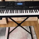 Černý digitální klavír značky YAMAHA, model PSR-E463, umístěný na černém X-stojaně. Nástroj má bílé a černé klávesy a horní panel s displejem, tlačít…
