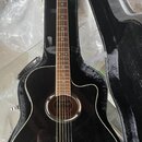 Černá akustická kytara s cutawayem v černém tvrdém pouzdře. Na hlavě hmatníku je bílý nápis YAMAHA. Kytara má tmavě hnědý hmatník a dřevěný kobylník.…