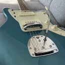 Modře lakovaná elektrická kytara s krémovým pickguardem a hmatníkem z tmavého dřeva. Na kovovém mostě je vyryto logo Fender a nápis Pat. № 2,523,925.…